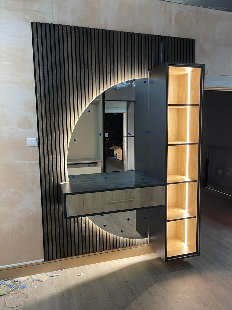 Bespoke slatted timber feature wall with backlit oak shelving by Delta Construction